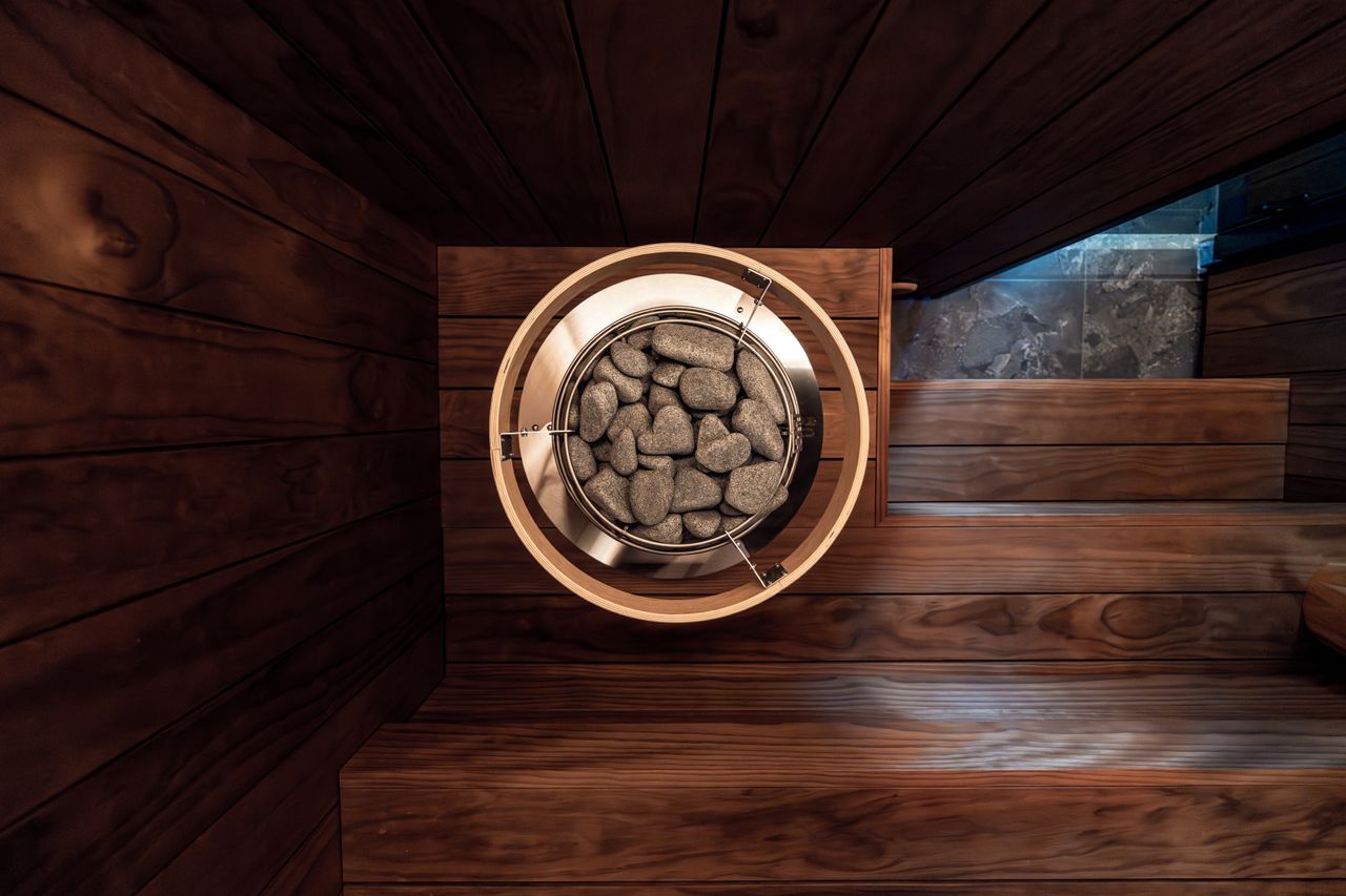 journey Stylish indoor sauna featuring a modern electric heater surrounded by dark wooden walls and sauna benches.
