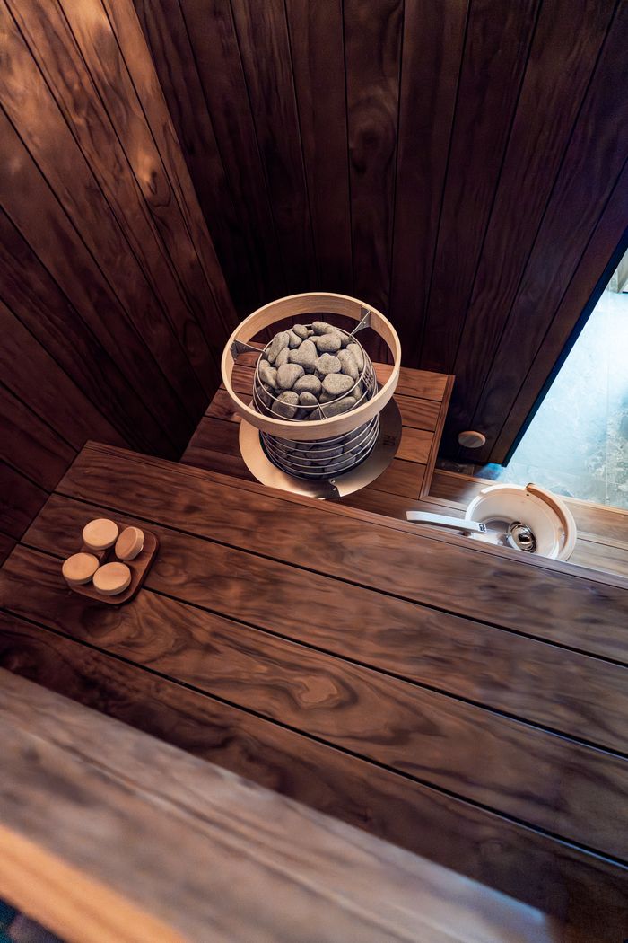 who-we-are Elegant indoor sauna featuring modern Nordic design with wooden benches and an electric heater.